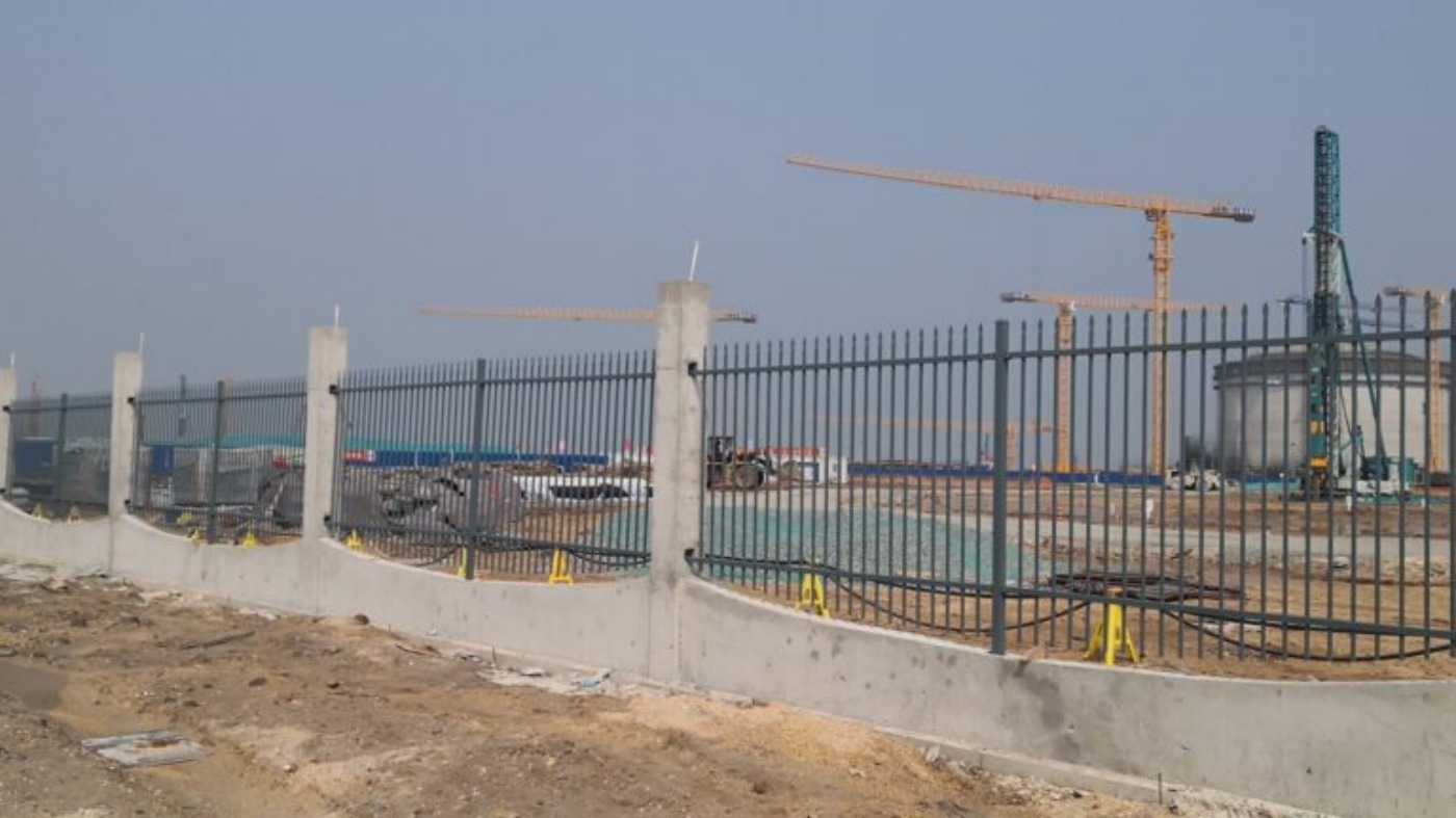 Perimeter fence installation with concrete foundation during construction