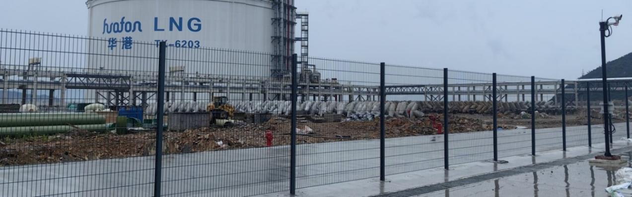 Industrial perimeter fencing at an LNG or petrochemical facility exposed to coastal conditions