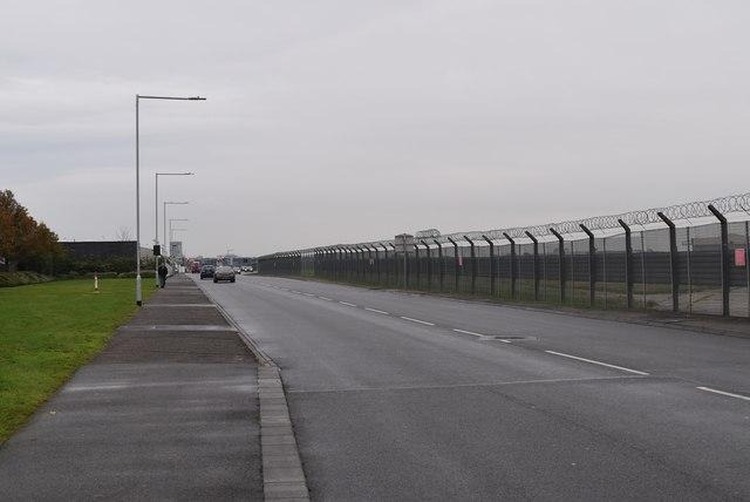 Long airport perimeter fence beside an access road