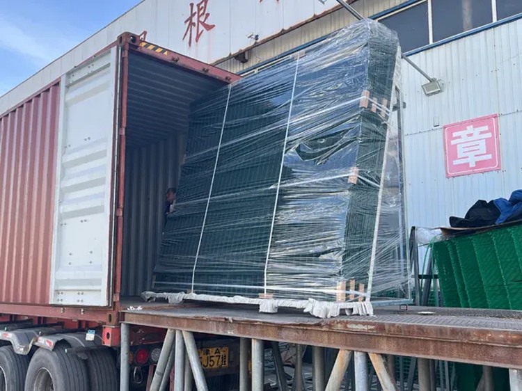 Wrapped steel fence panels on a pallet being loaded into a shipping container