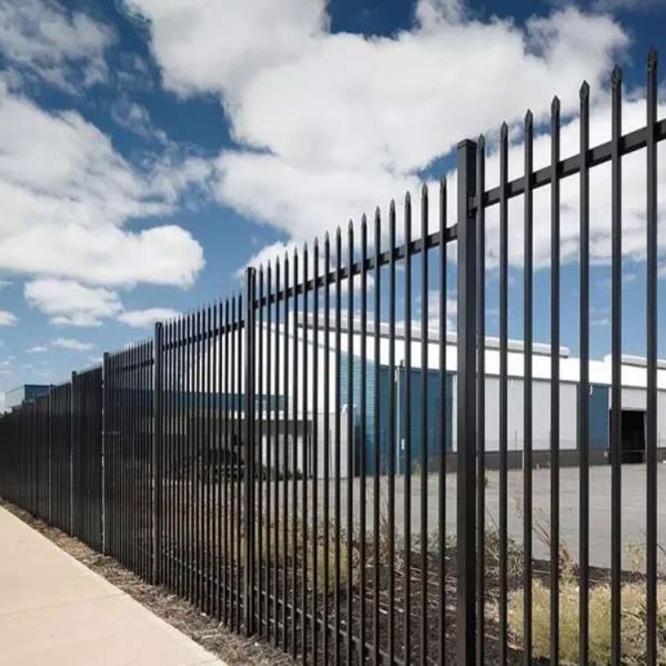 Black tubular steel fencing installed alongside an industrial building